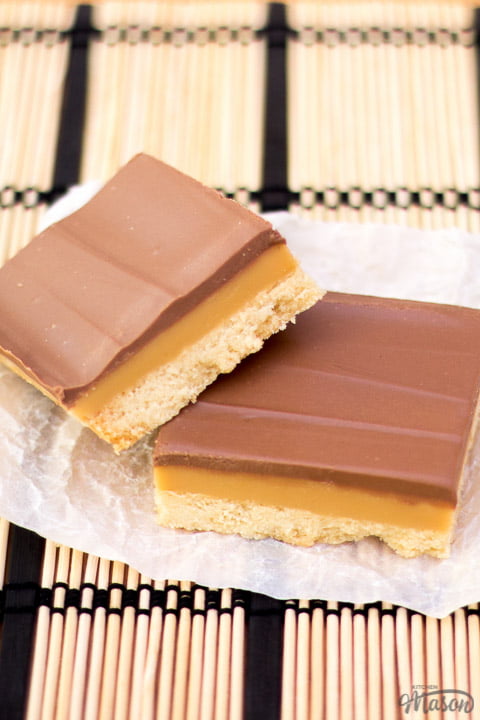 Millionaire's shortbread bar leaning on another bar on scrunched up white baking paper