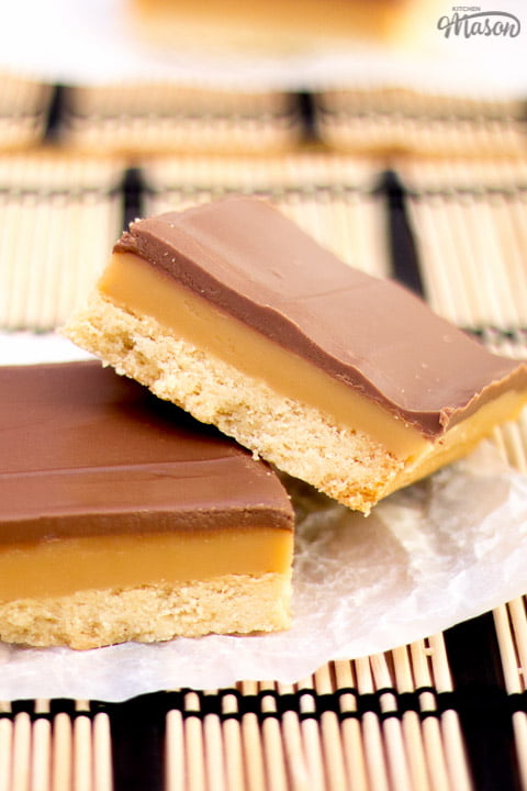 Millionaire's shortbread bar leaning on another bar on scrunched up white baking paper
