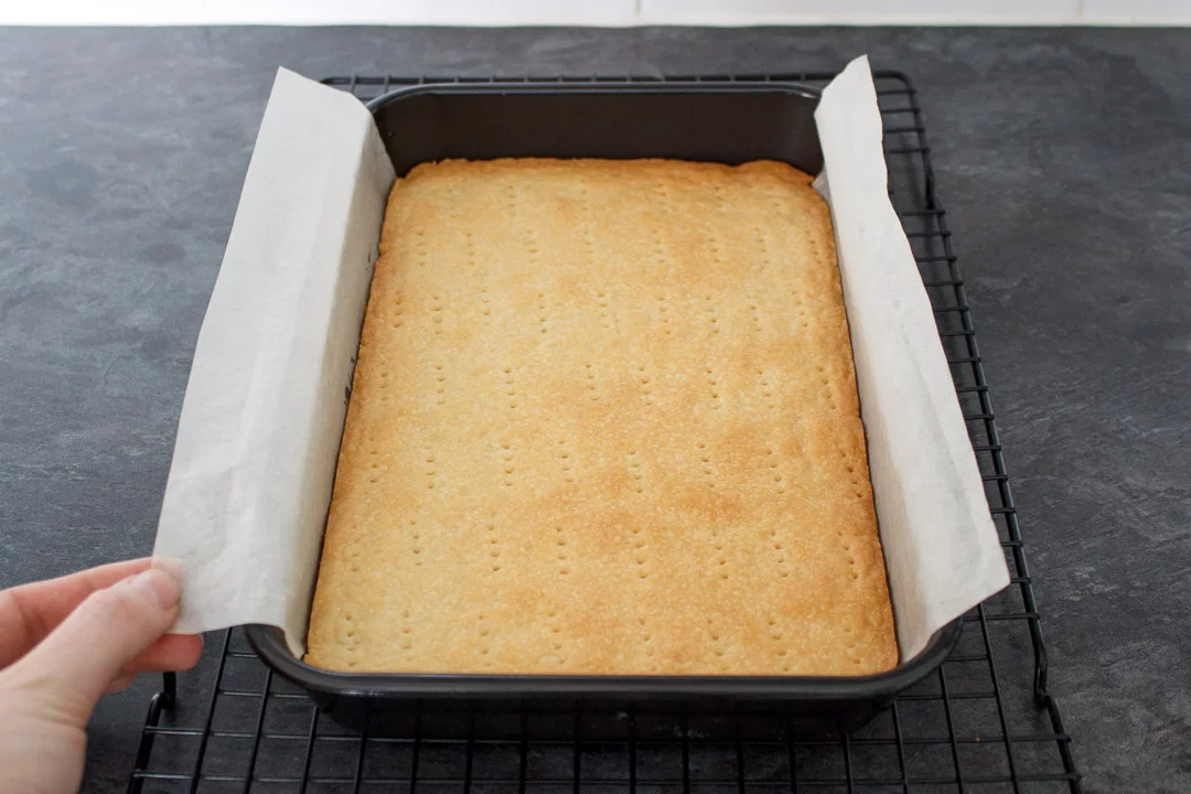 Baked shortbread base in a lined rectangular baking tin