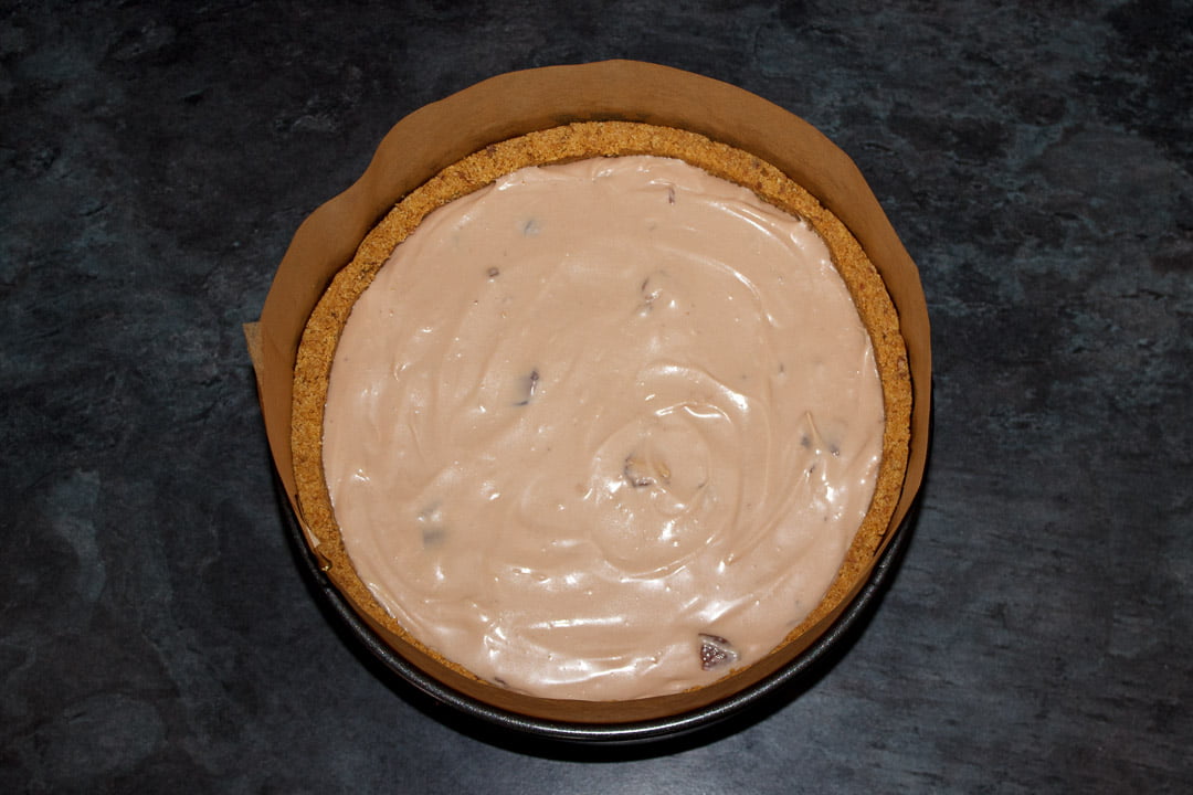 Kinder Bueno cheesecake in a lined springform pan ready to set in the fridge