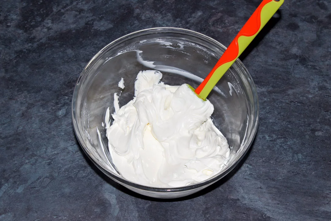 Softened cream cheese beaten in a glass bowl with a rubber spatula
