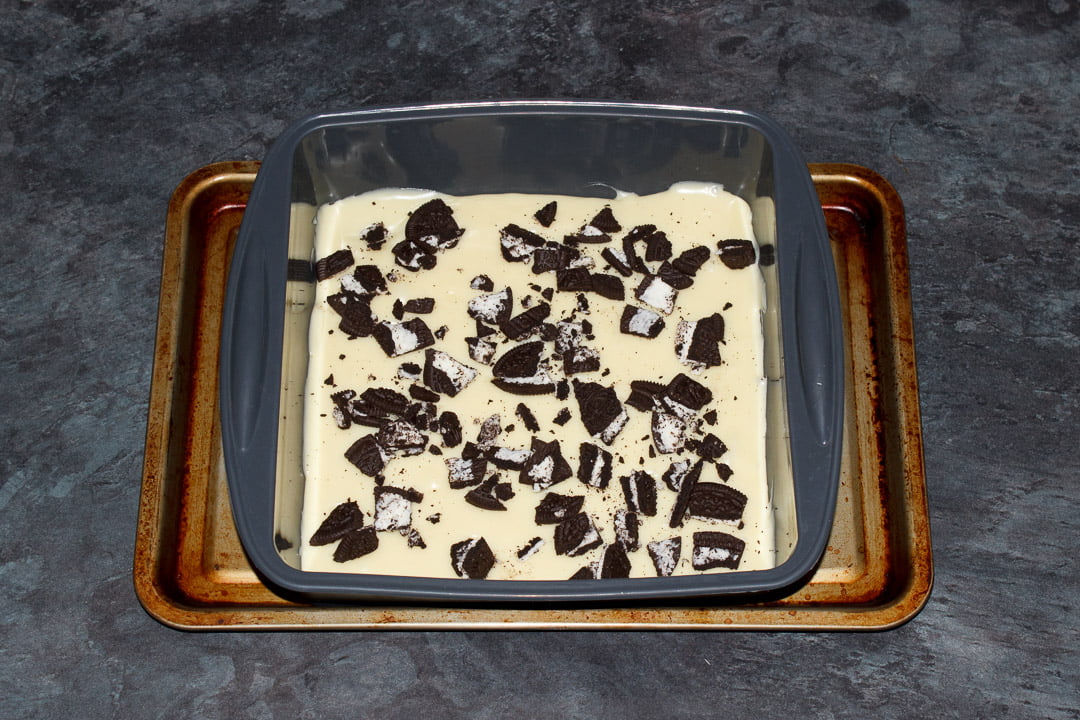 White chocolate fudge in a silicone baking pan with roughly chopped Oreos scattered on top