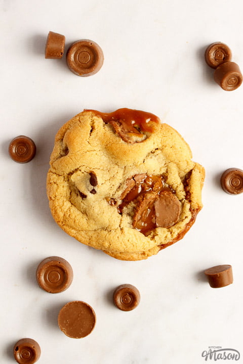 A Rolo cookie on a white marble worktop with large and small Rolos scattered around it