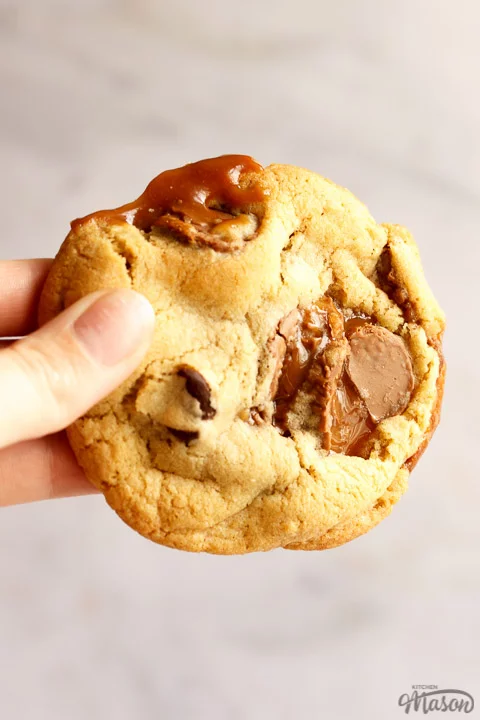 A Rolo cookie being held up in front of a white/grey background