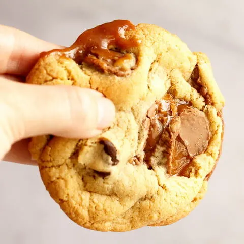 A Rolo cookie being held up in front of a white/grey background
