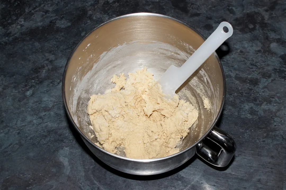 Cookie dough in the bowl of an electric stand mixer with a spatula