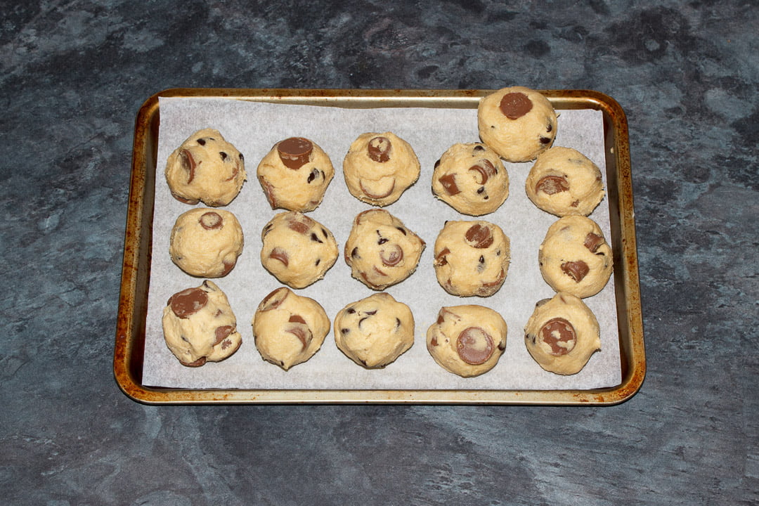 Rolo cookie dough balls on a small lined baking tray