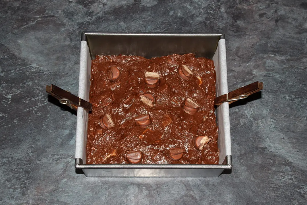 Kinder Bueno Brownie batter in a lined square baking tin with Kinder Bueno Bar pieces pushed into the top