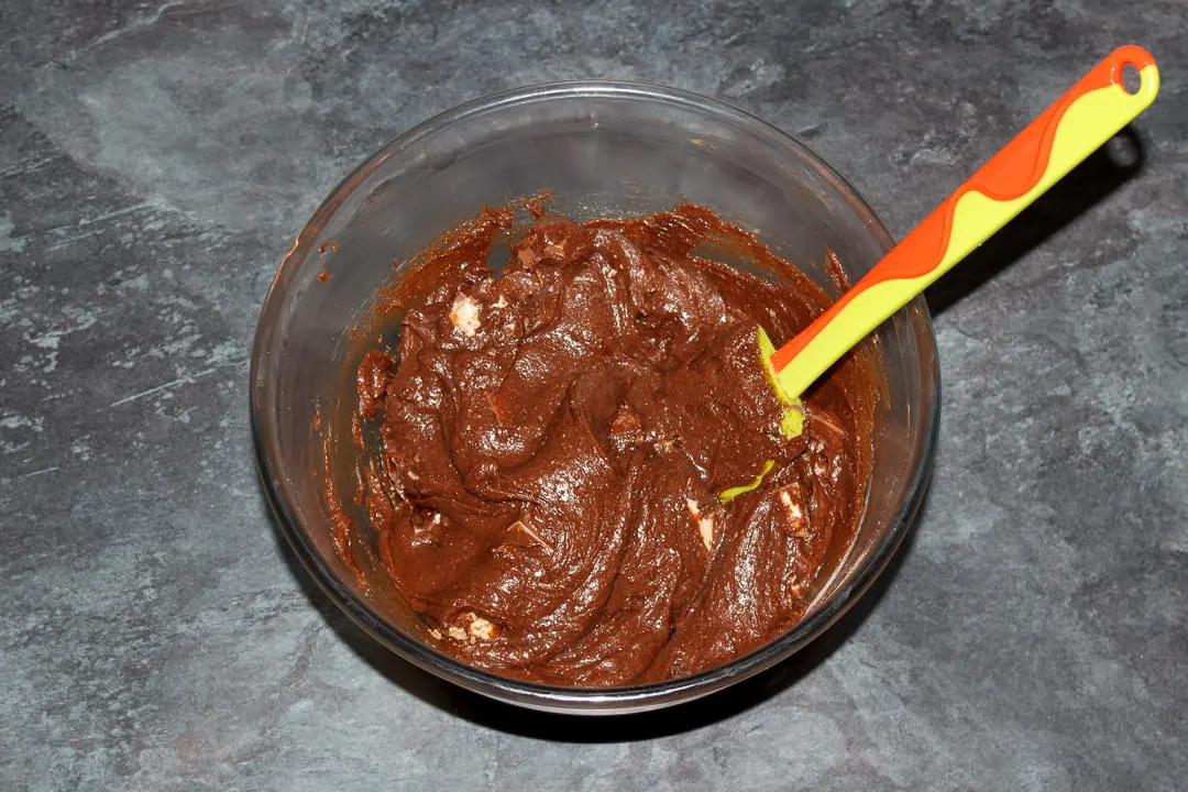 Kinder Bueno Brownie batter in a glass bowl with a green spatula