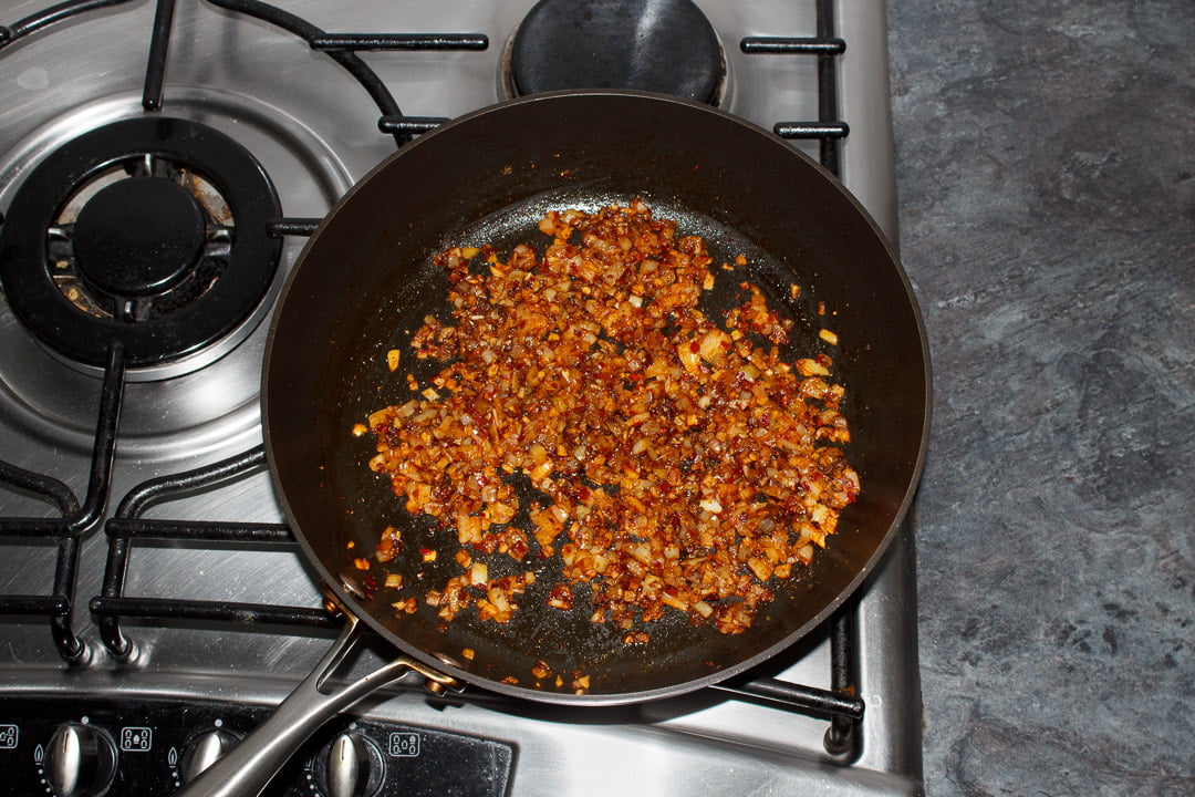Onion, garlic, ginger and chilli frying in a large saucepan with garam masala, turmeric and brown sugar