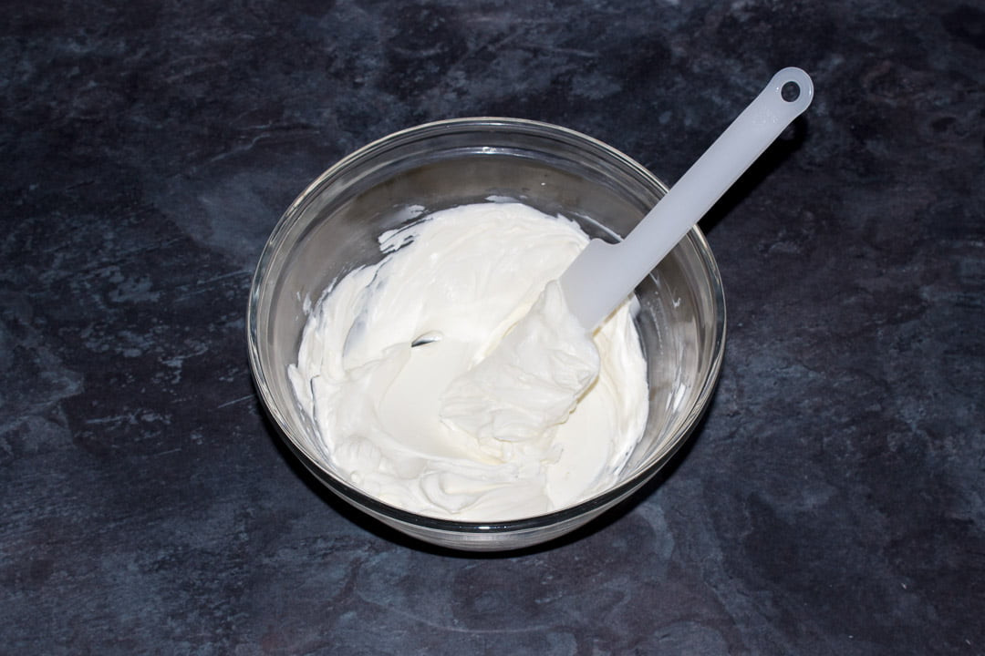 Softened cream cheese in a glass bowl with a spatula