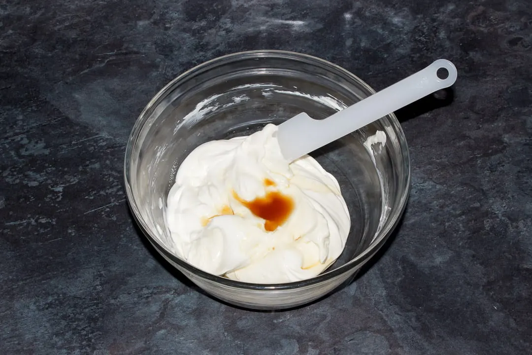 Cream cheese, sugar, soured cream and vanilla extract in a glass bowl with a spatula