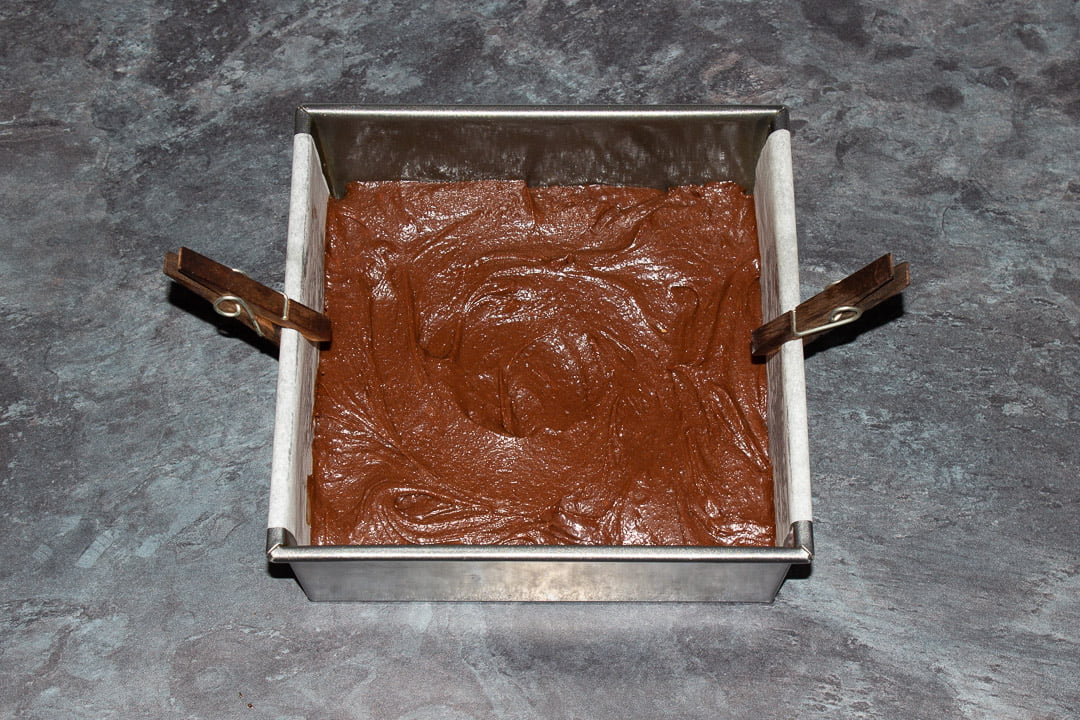 Brownie batter smoothed out into a lined square baking tray