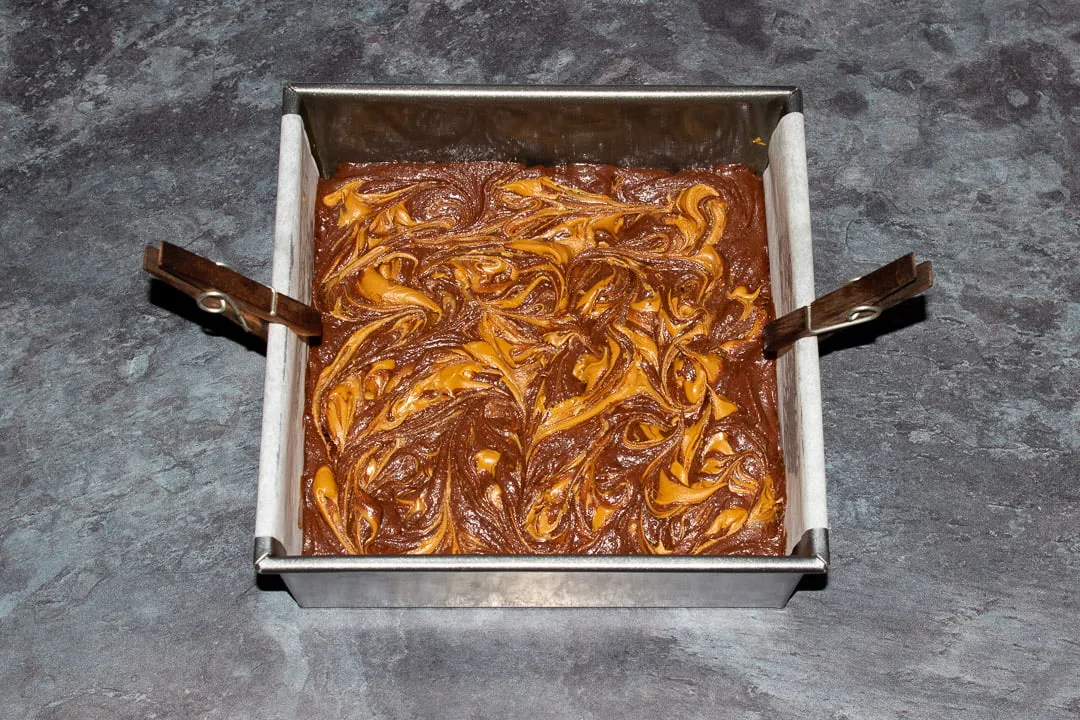 Biscoff brownie batter in a lined square baking tin ready for the oven
