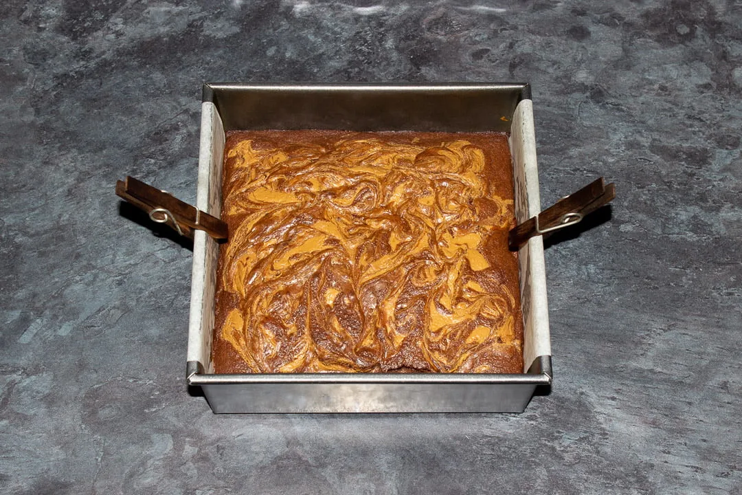 Baked Biscoff brownies in a lined square baking tin