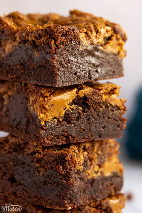 A close up of a stack of 3 Biscoff brownies with a blue linen napkin in the background