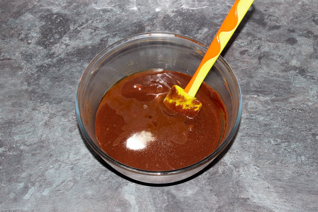 Melted dark chocolate, butter, eggs, sugar, vanilla and salt in a glass bowl with a rubber spatula