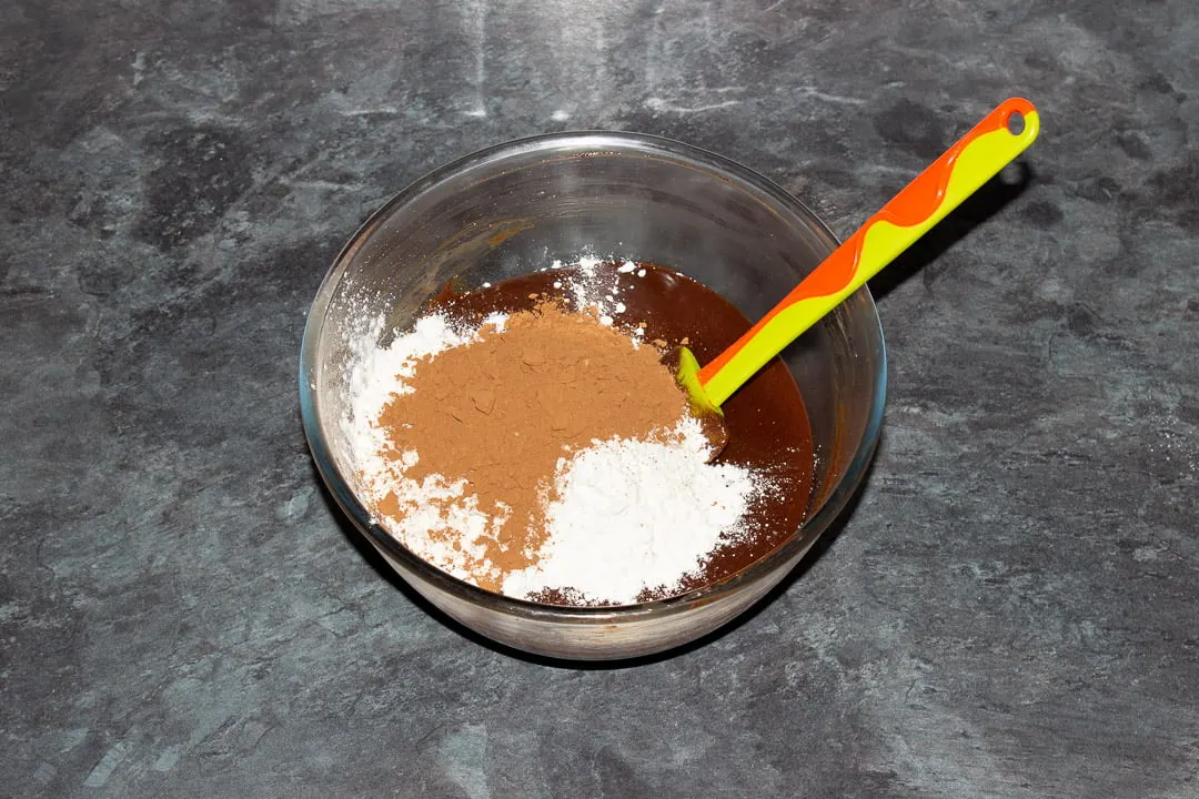 Melted dark chocolate, butter, eggs, sugar, vanilla, salt, cocoa powder and flour in a glass bowl with a rubber spatula