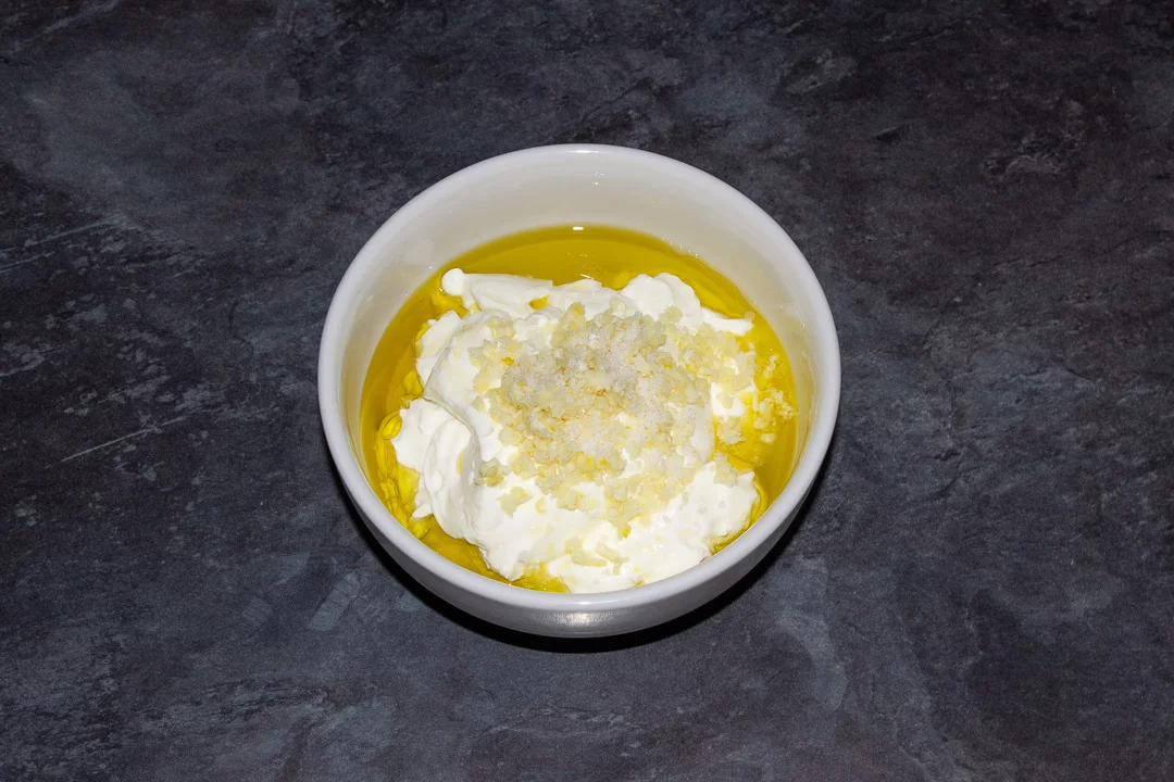 Greek yoghurt, olive oil, garlic, lemon juice and salt in a small white bowl