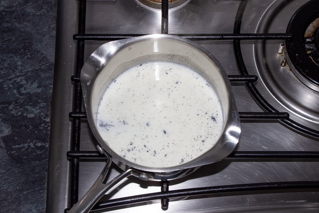 Milk in a saucepan over a low heat being infused with a vanilla pod