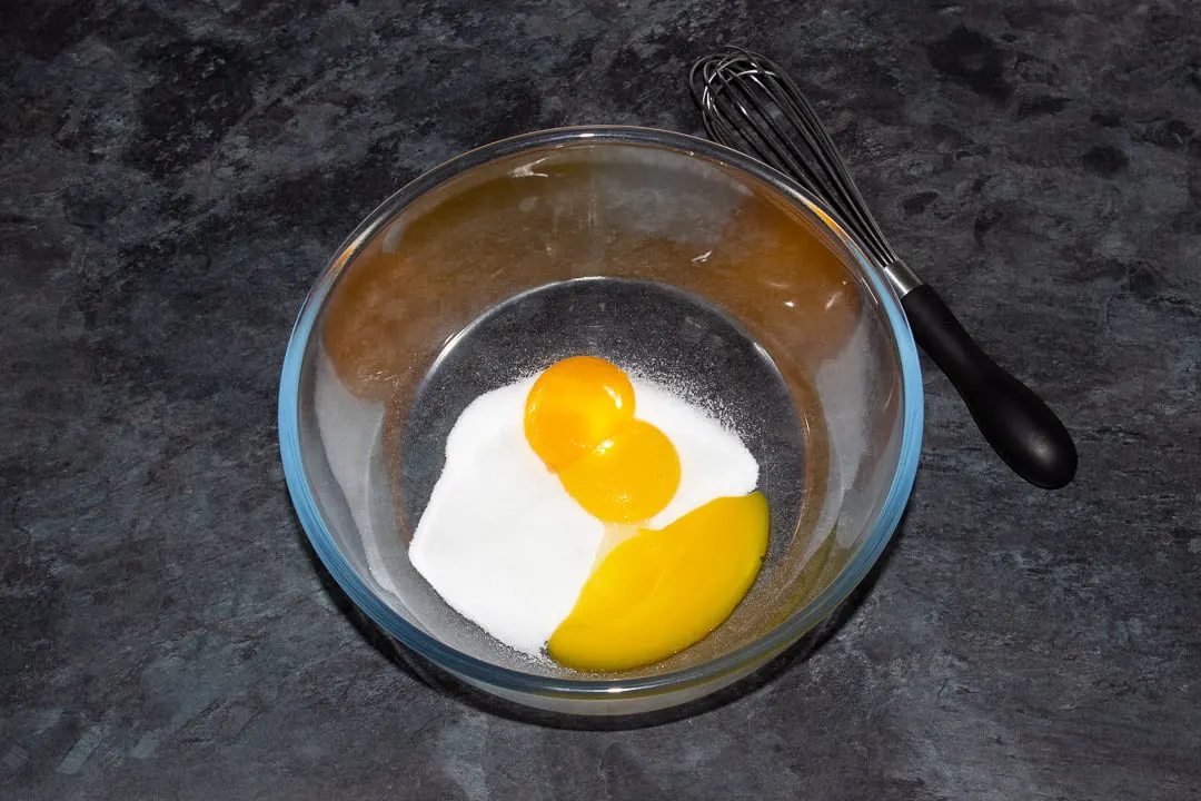 Egg yolks and sugar in a glass bowl
