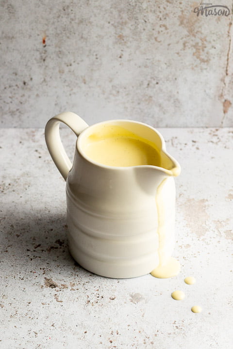 Homemade custard in a white jug with drips running down the front
