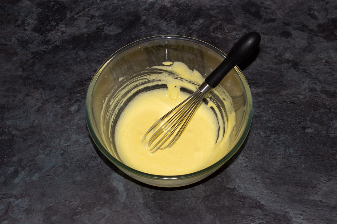 Egg yolks and sugar in a glass bowl that have been beaten until pale and slightly fluffy