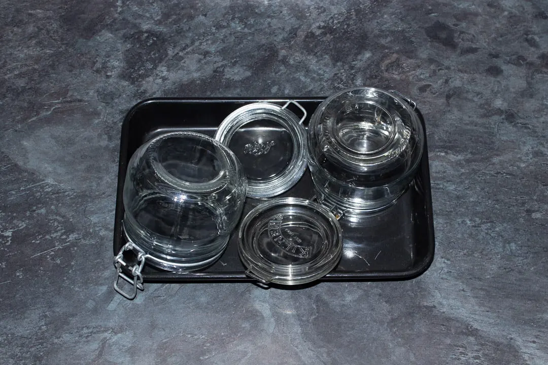 Two clean jars in a baking tray ready to be sterilised in the oven