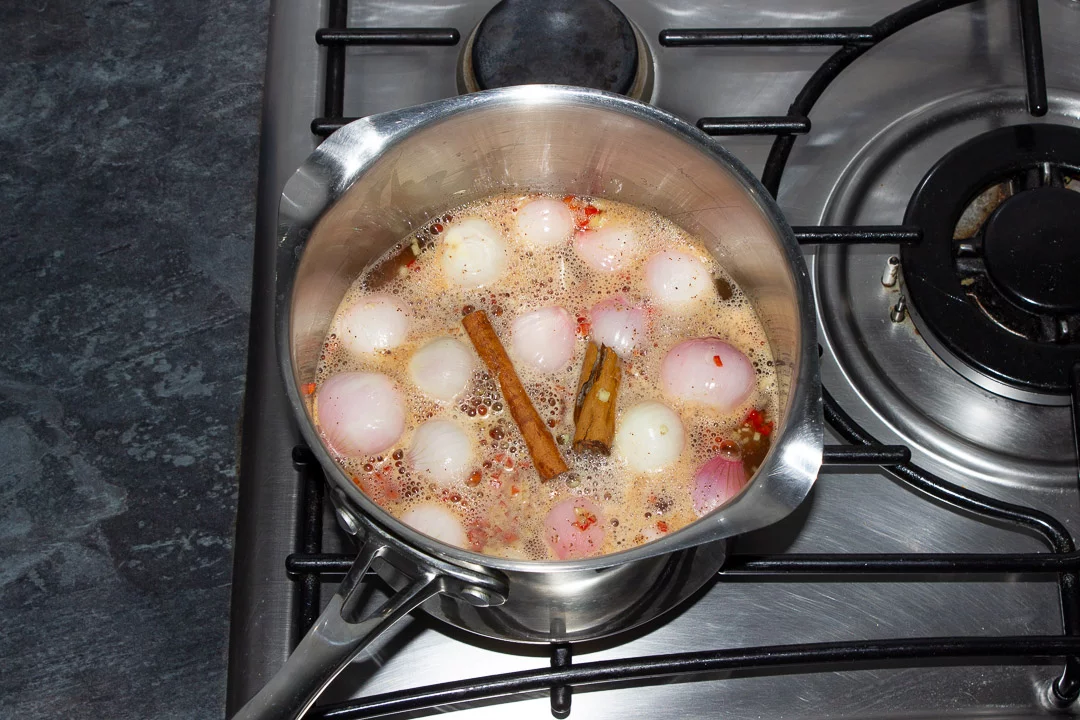 Peeled and trimmed baby shallots in a large saucepan simmering on the stove with white wine vinegar, sugar, chilli, chinese 5 spice, ginger and cinnamon.