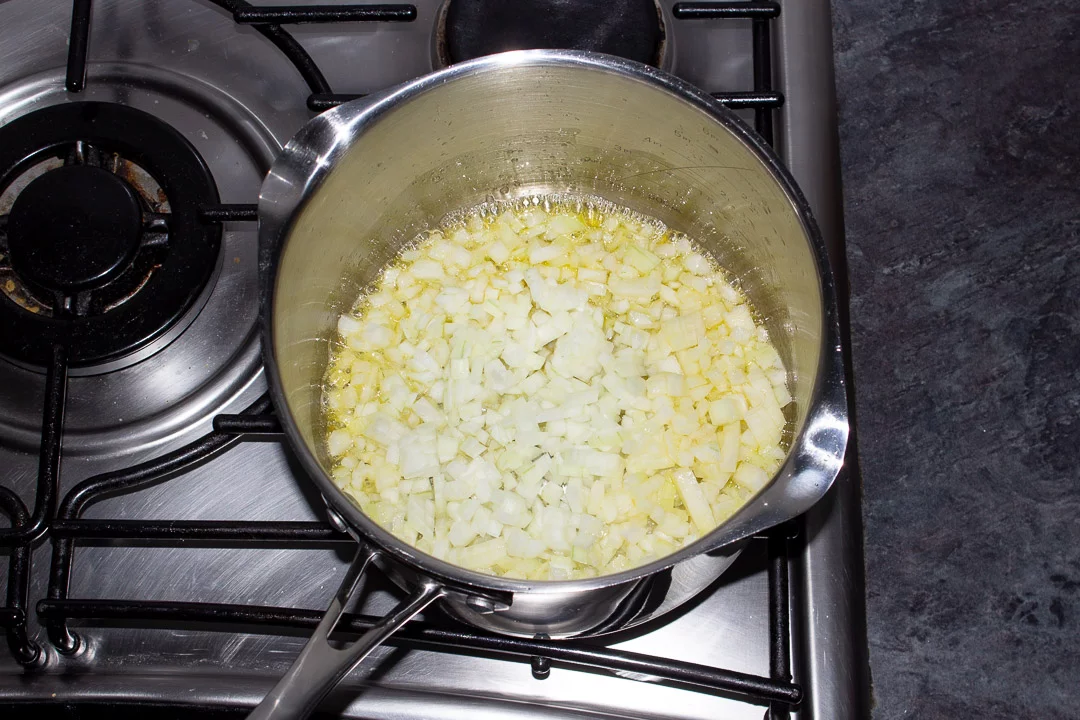 Onions frying in butter in a saucepan on a hob