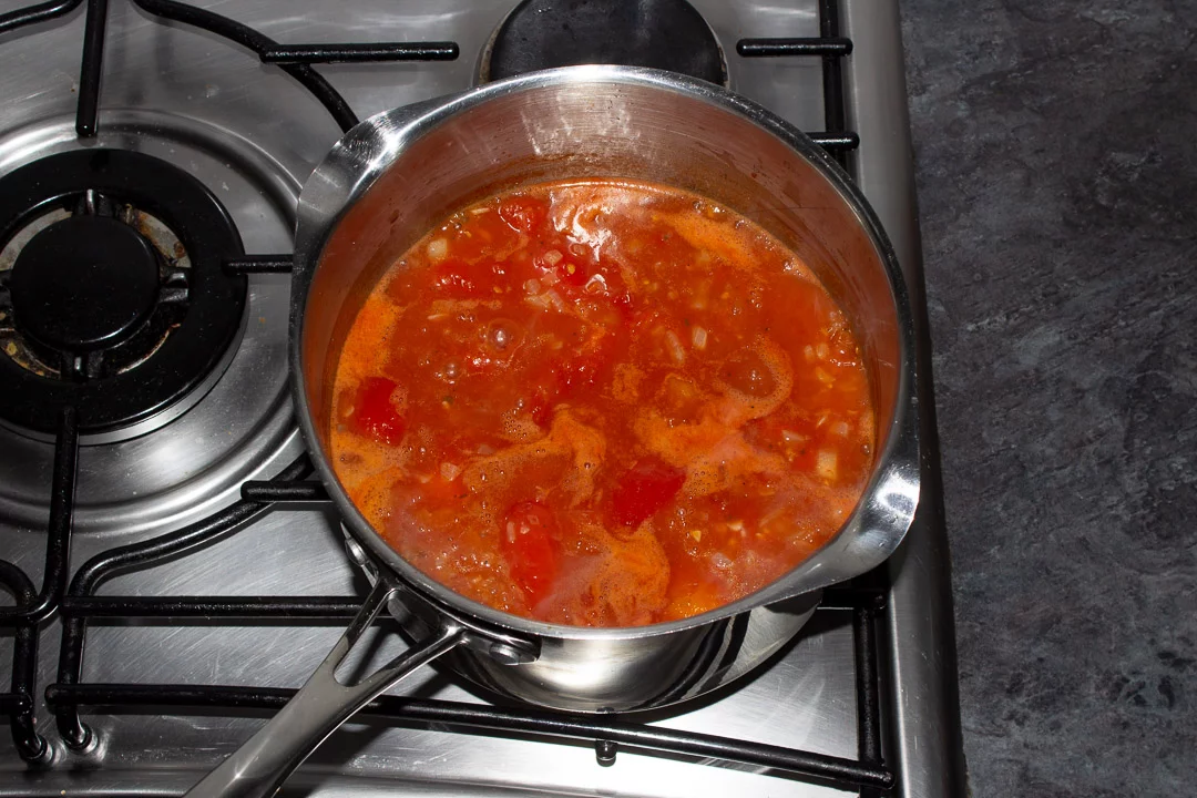Tomato soup ingredients simmering in a saucepan on a hob