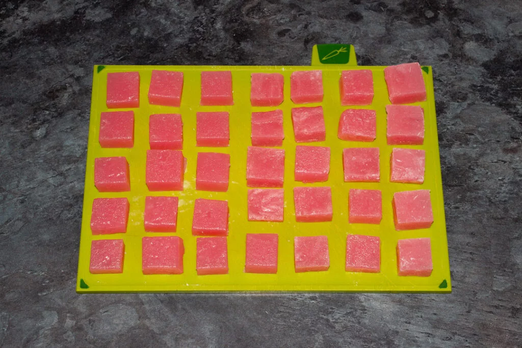 Turkish delight cut into cubes resting on a green chopping board