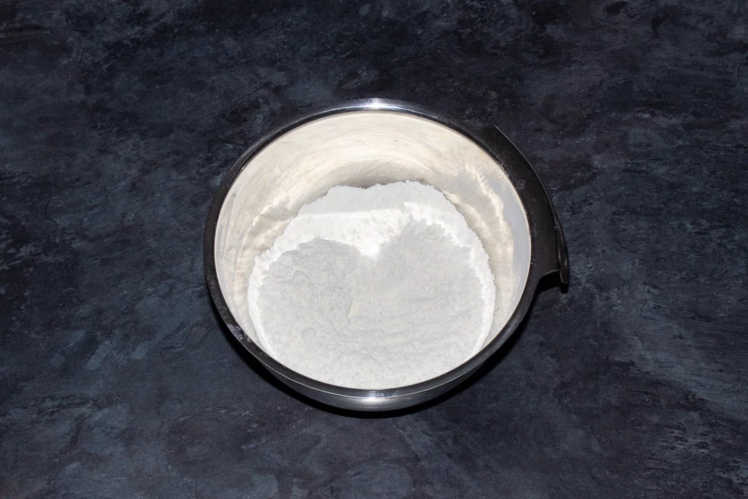 Flour, bicarbonate of soda, baking powder and salt in a small metal bowl on a kitchen worktop