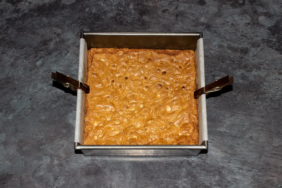 Baked white chocolate Biscoff blondies in a lined square baking tin