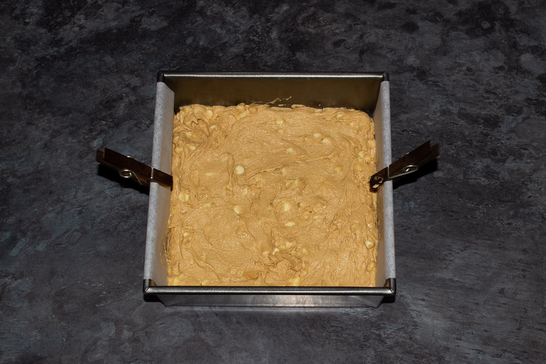 Biscoff blondie batter spread out in a lined square baking tin