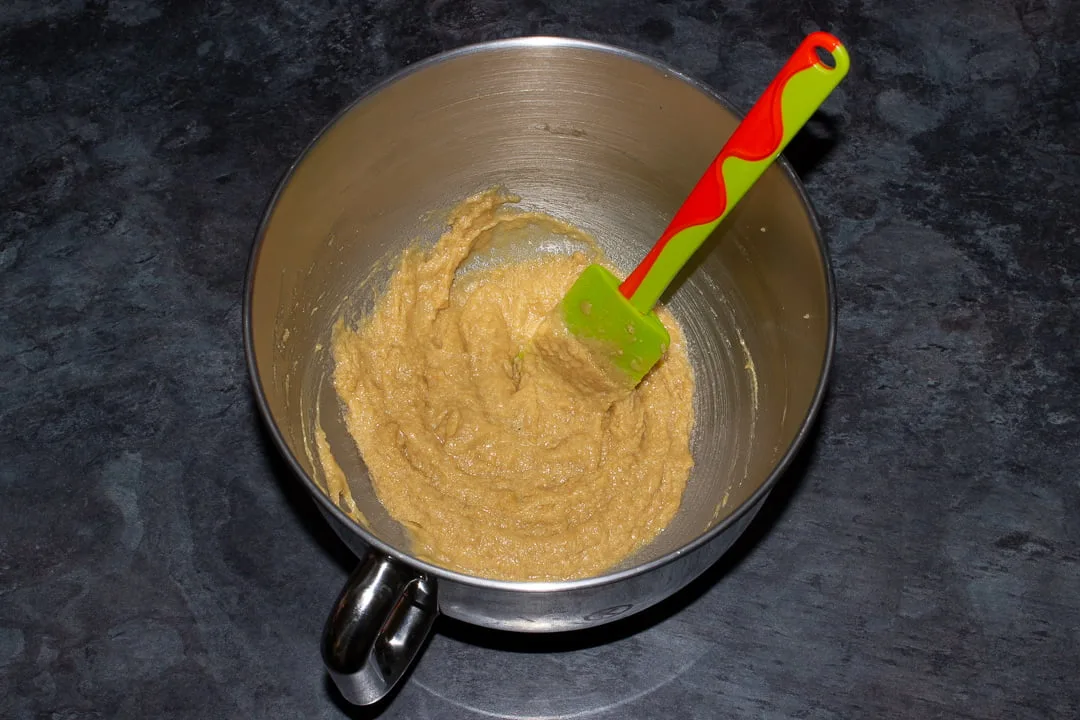 Creamed butter and sugar beaten with egg and vanilla in the bowl of an electric stand mixer with a green rubber spatula