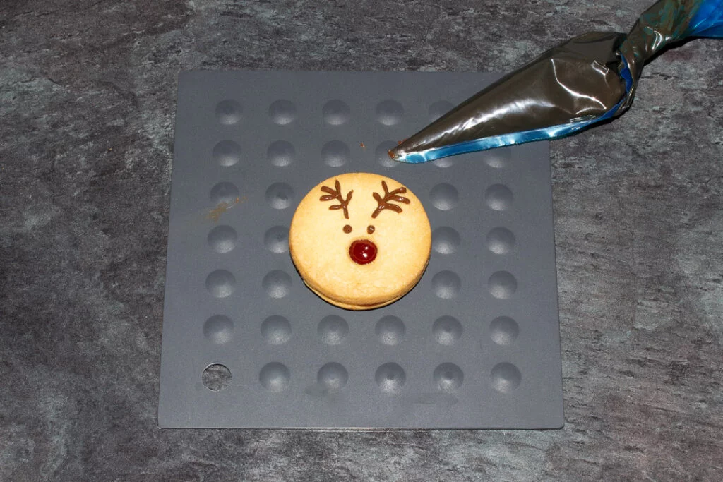 A reindeer cookie with the chocolate eyes and antlers piped on