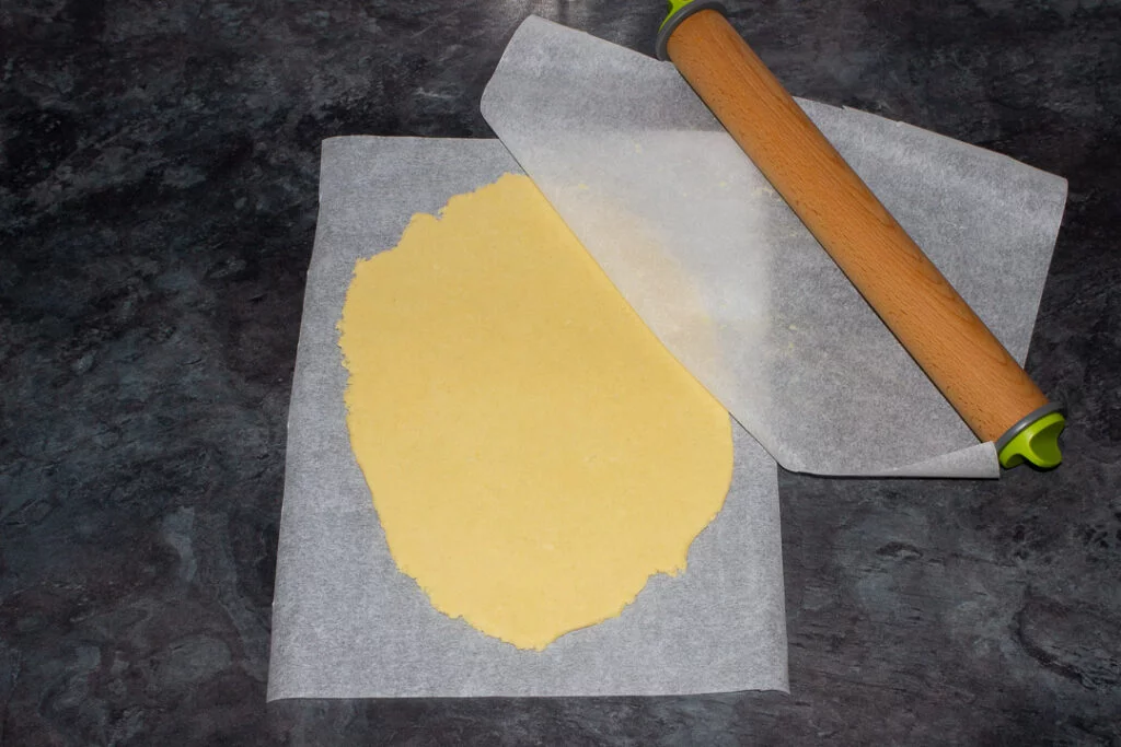 Cookie dough rolled out between two sheets of baking paper ready for cutting