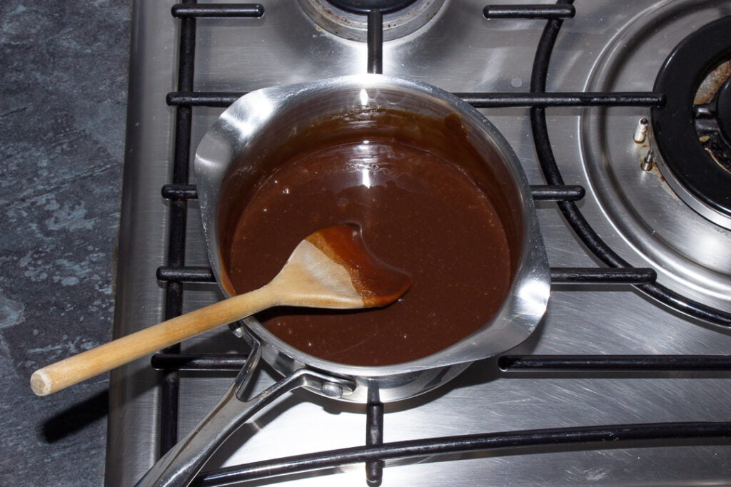 Warm Baileys chocolate sauce in a small saucepan on the hob