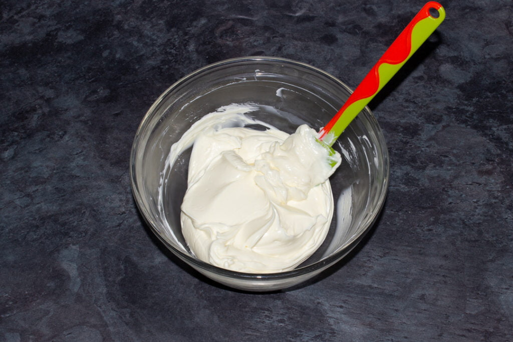 Cream cheese and icing sugar that's been mixed together in a glass bowl