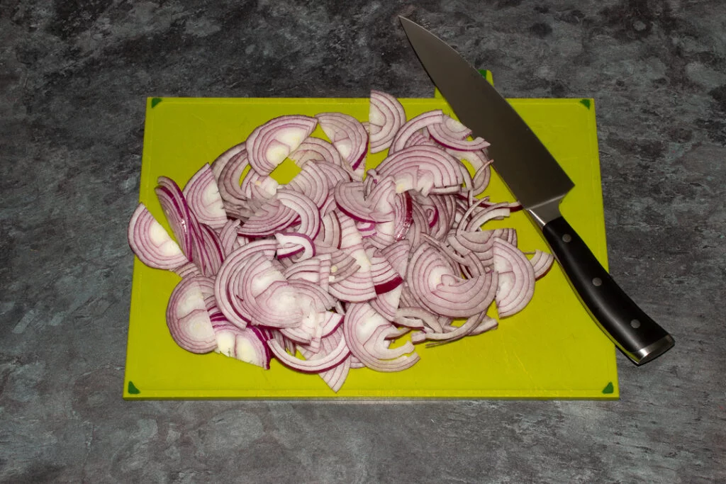 chopped red onions on a green chopping board with a sharp knife