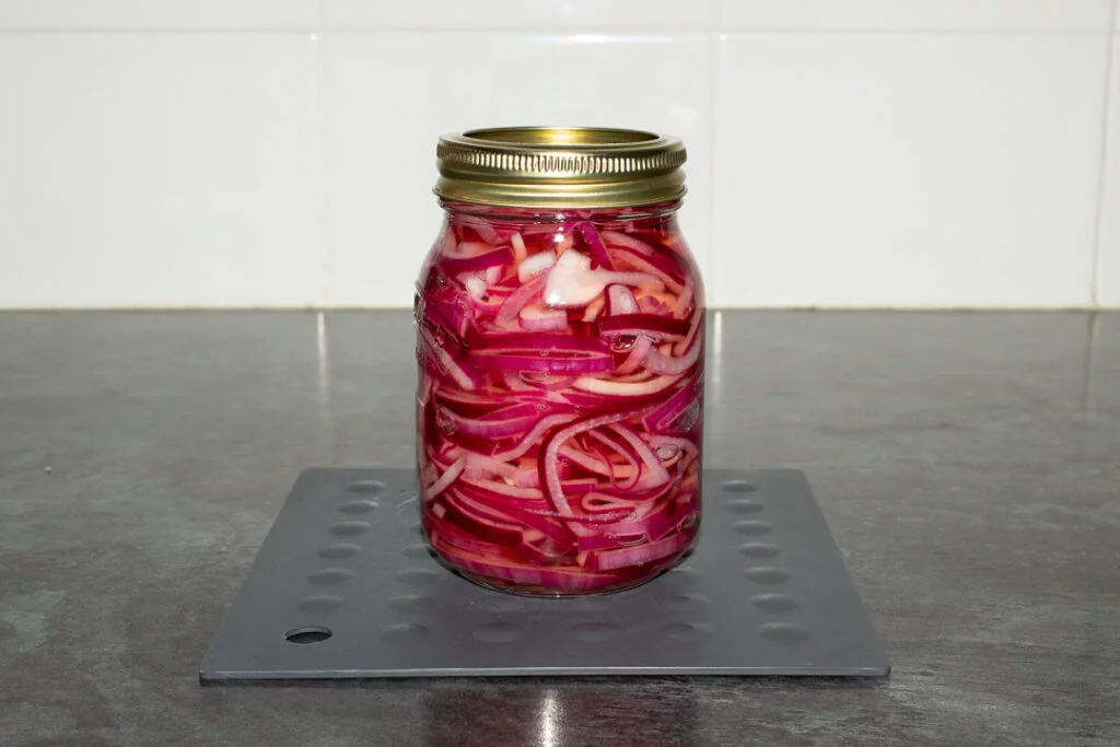 A sealed glass jar of pickled red onions