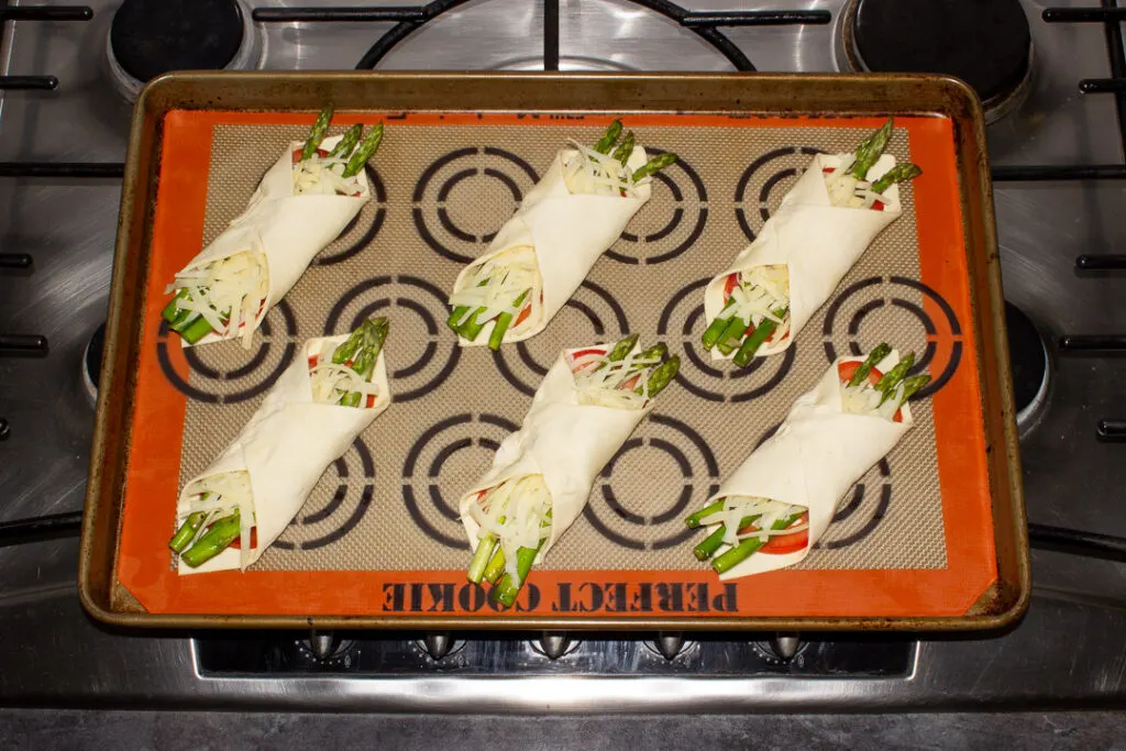 6 asparagus puff pastry parcels on a lined baking tray
