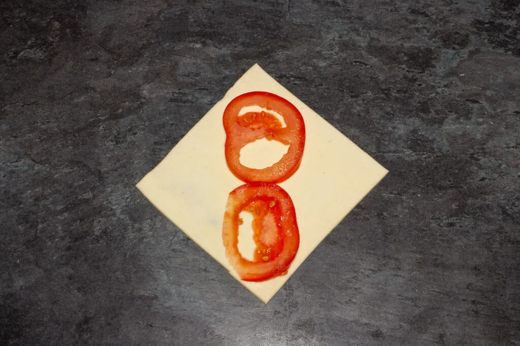 A square of puff pastry on the diagonal with two thin slices of tomato on top