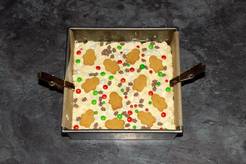 Christmas rocky road in a lined square baking tin topped with mini gingerbread men and Christmas sprinkles