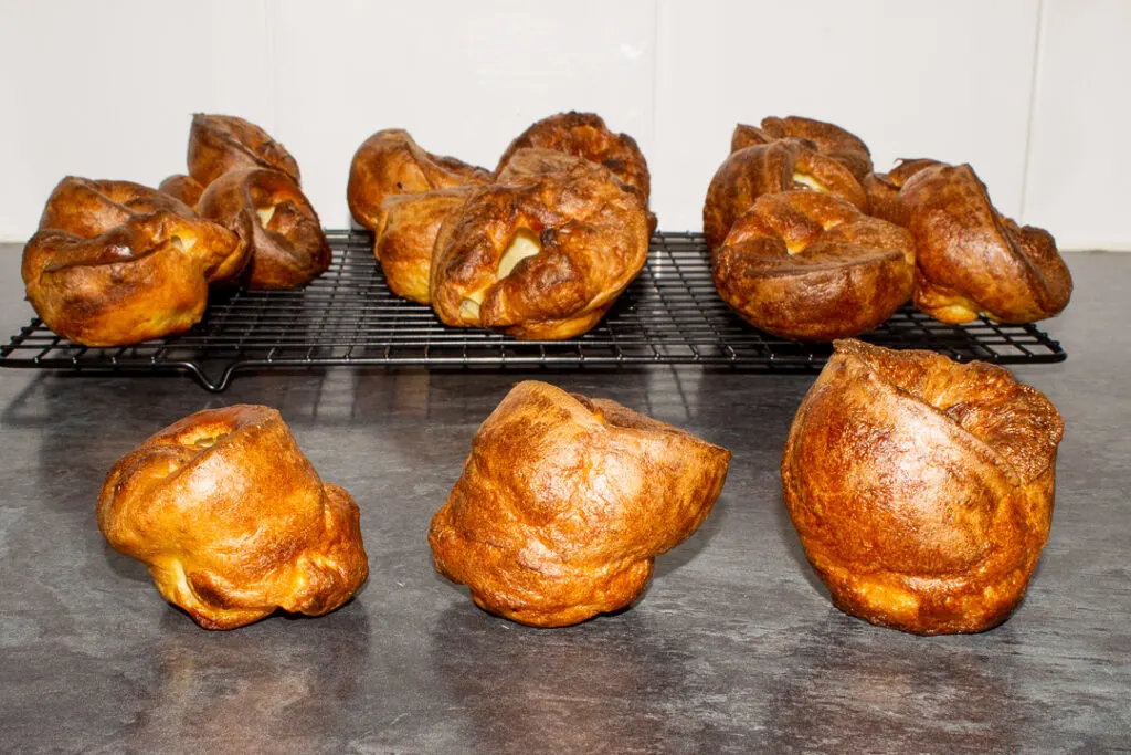 Yorkshire puddings on a wire cooling rack with 3 in front showing the size effect that different resting times have.