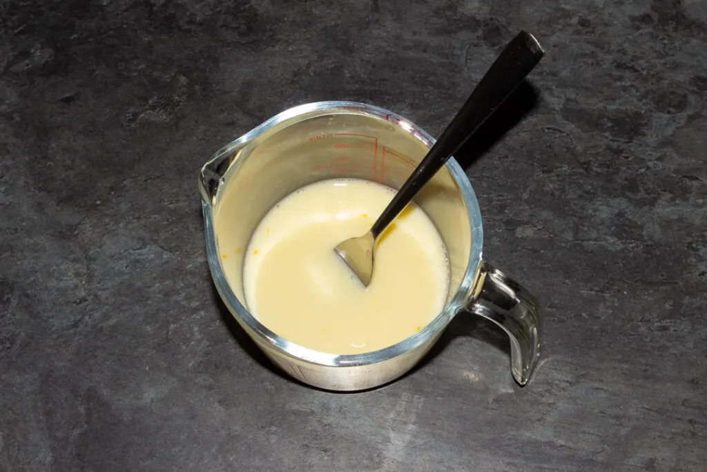 Egg, milk and water beaten together with a metal fork in a glass jug