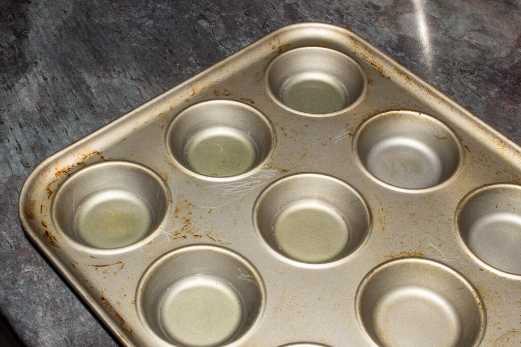A Yorkshire pudding pan where 5 holes are filled with a small amount of oil
