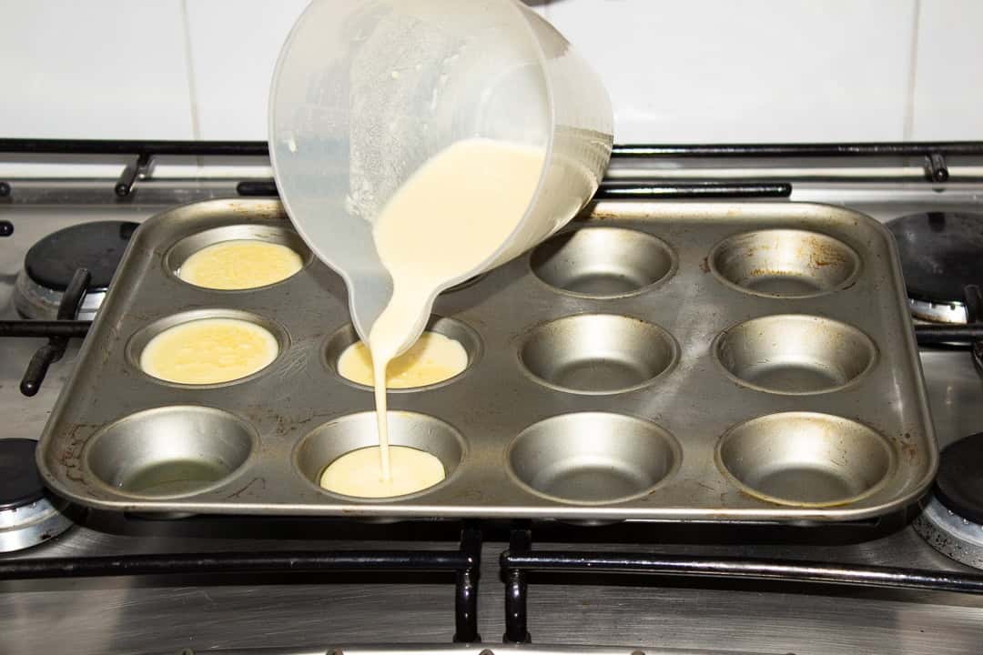 Yorkshire pudding batter being poured into a hot tin.