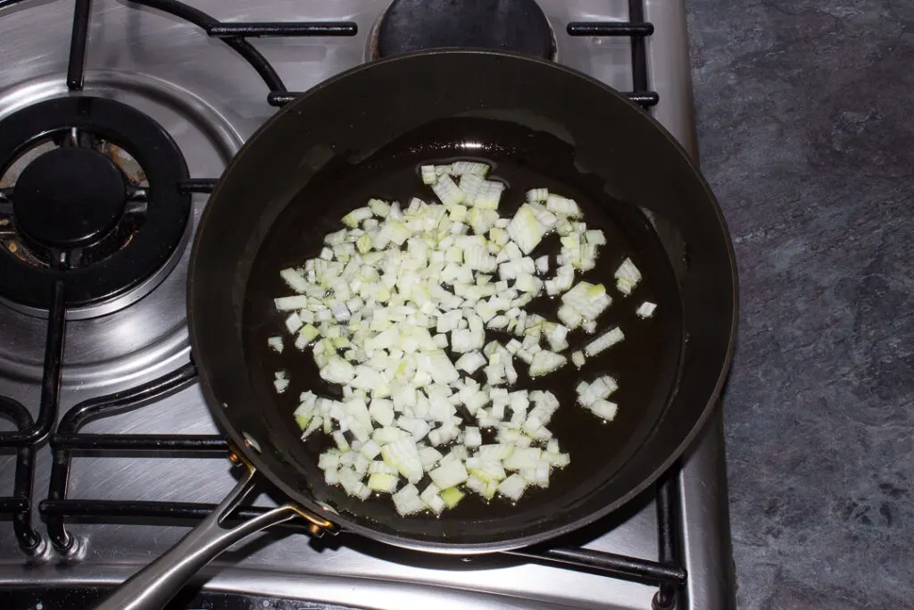 Onion and olive oil in a frying pan on the stove
